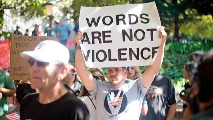 Person holding poster that reads Words are not violence